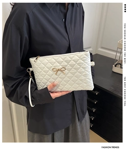 Détail du matelassage blanc et du nœud doré sur le grand sac à main élégant