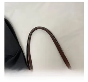 Detail of deep brown leather shoulder strap with reinforced stitching and smooth edge oil