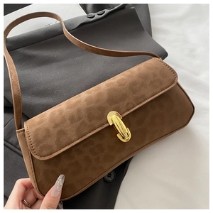 Detailaufnahme der braunen Wildledertasche mit Goldverschluss auf grauem Blazer