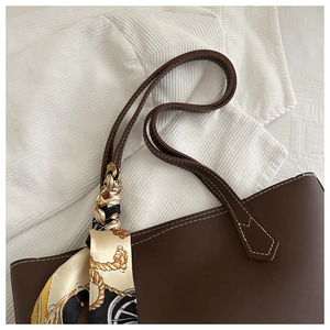 Detail of dark brown tote bag with white contrast stitching and silk scarf accessory
