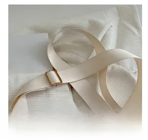 Detail of adjustable beige woven shoulder strap with gold metal buckle and spring hook