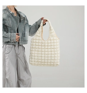 Close-up of beige quilted tote bag showing its padded texture and soft puffy handle
