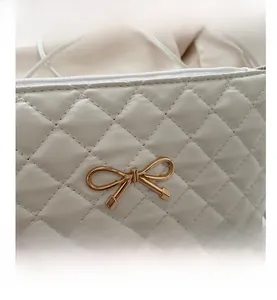 Gros plan sur la texture en cuir blanc matelassé et boucle dorée en forme de nœud