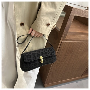 Detail of leopard print baguette bag featuring a gold cylindrical twist lock and soft fabric