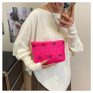 Detailed texture of hot pink pleated corduroy clutch featuring black butterfly embroidery