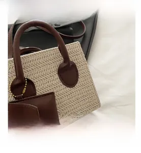 Detail of woven straw handbag with brown leather handles and mini accessory pouch