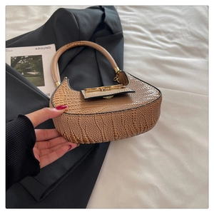 Detail of tan crocodile texture crescent bag with gold metal buckle and sturdy strap