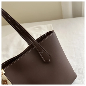Detailed close-up of dark brown tote bag with contrast stitching and floral scarf decor
