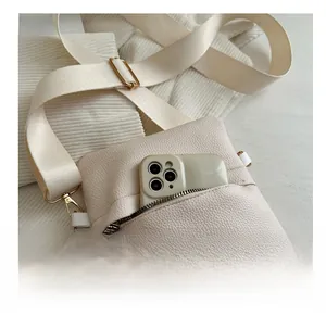 Detail of beige lychee texture crossbody bag showing front zipper pocket capacity for phone