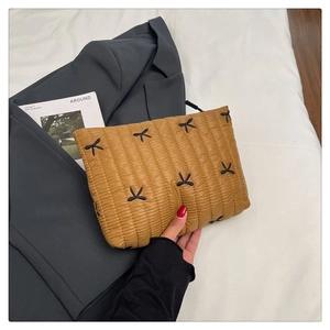 Macro view of mustard yellow quilted clutch with black bow stitching on fabric