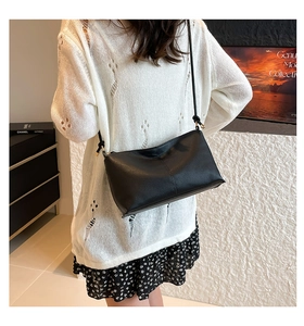 Detailed view of black litchi texture leather underarm bag with gold metal hardware