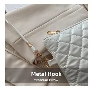 Détail du crochet doré brillant et des coutures matelassées sur le sac en cuir blanc