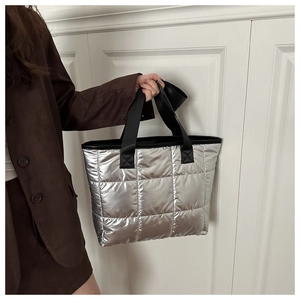 Détail du sac cabas matelassé argenté avec anses noires et finition métallique