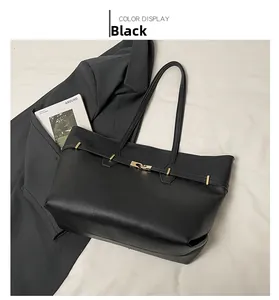 Detail of a large black matte leather tote bag with gold buckle on office blazer background