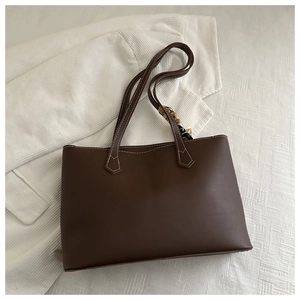 Close-up of brown tote bag with white contrast stitching and a silk scarf accent