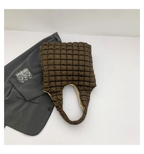 Detail of dark brown quilted puffer tote bag with soft bubble texture and beige lining
