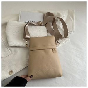 Macro shot of beige lychee grain leather crossbody bag with nylon strap and metal zipper