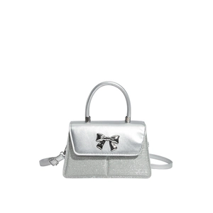 Silver sequin handbag with metal bow detail and crossbody strap on white background