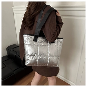 Sac fourre-tout matelassé argenté porté par un mannequin avec une finition brillante