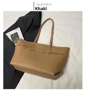 Detail shot of khaki leather tote bag featuring metal buckle and matte texture on white backdrop
