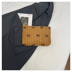 Detail of ginger quilted clutch with bow decoration and water-resistant nylon texture