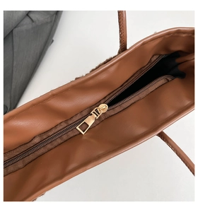 Gros plan détaillé de la fermeture éclair dorée sur le sac cabas marron en cuir