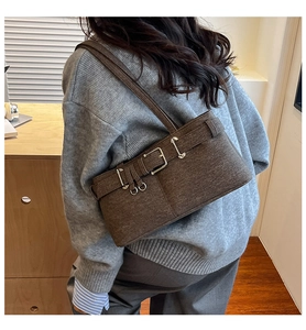 Detail of a dark brown wool shoulder bag with decorative metal buckles and retro texture