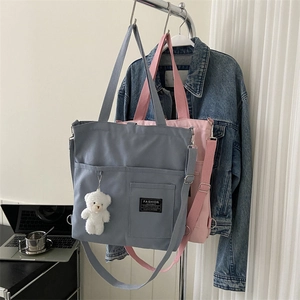 Minimalist canvas tote bag with adjustable strap and bear pendant in casual style