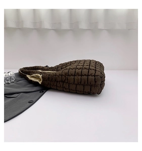 Macro detail of brown quilted bubble tote bag featuring premium padded square texture