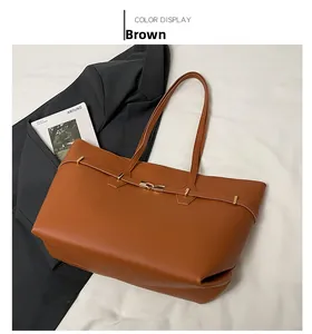 Flat lay of brown tote bag with metal buckles on white cloth next to a black blazer