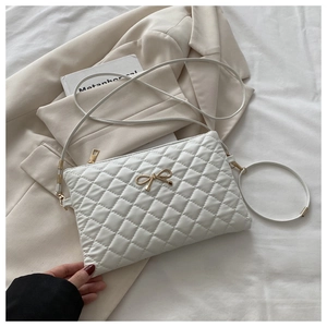 Détail du sac bandoulière matelassé blanc avec fermoir nœud doré et fine bandoulière
