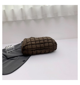 Detail of coffee brown quilted puffer tote bag fabric with soft square texture