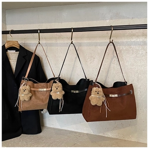 Detailed view of matte texture tote bags with plush bear charms and metal buckle straps