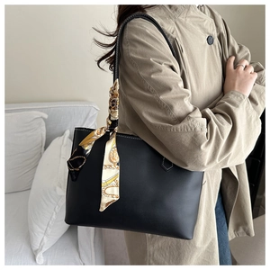 Detail of black pebbled leather tote bag featuring a decorative vintage print silk scarf