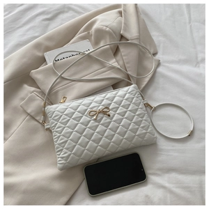 Sac bandoulière matelassé blanc avec nœud doré montrant la capacité du téléphone