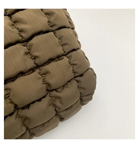 Detailed close-up of dark brown quilted puffer tote bag with square stitching texture