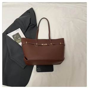 Detail of deep brown tote bag with gold metal buckle and leather texture