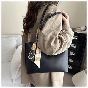 Detail of black leather tote bag with white stitching and floral scarf wrap on handle