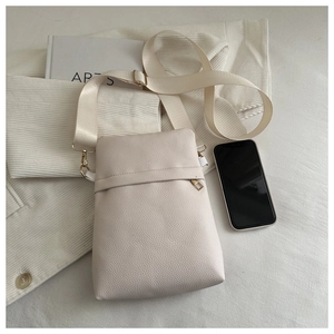 Close-up of cream crossbody bag with pebble texture and adjustable wide strap
