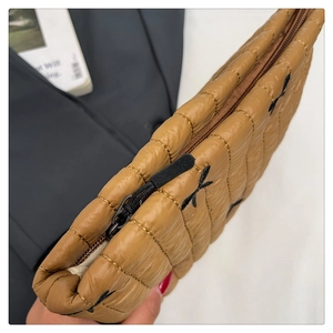 Close-up of brown quilted clutch with bow embroidery and metal zipper detail