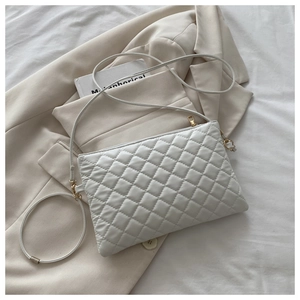 Détails de la couture matelassée et des finitions dorées sur le sac blanc en cuir
