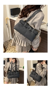 Detail view of charcoal fabric underarm bag featuring triple silver buckle straps