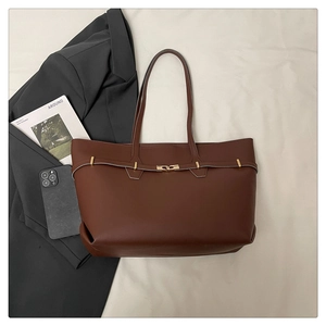 Detail of dark brown tote bag with gold metal buckles on soft beige fabric background