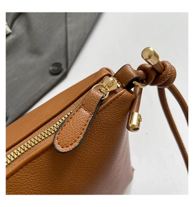 Macro view of caramel leather texture and gold metal zipper details on tote bag