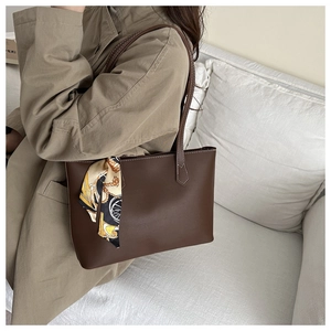 Detail of vintage brown leather tote bag with silk scarf on a trench coat shoulder