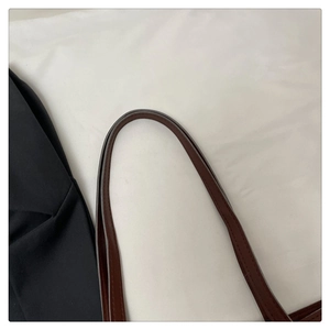 Detailed close-up of dark brown leather tote strap with fine stitching and oil edge
