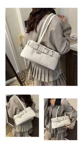 Detail of ivory faux leather shoulder bag with decorative buckle and pebble texture finish