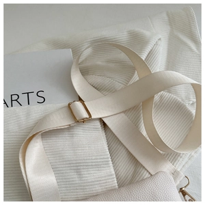 Detail of cream crossbody bag featuring lychee grain texture and gold metal hardware