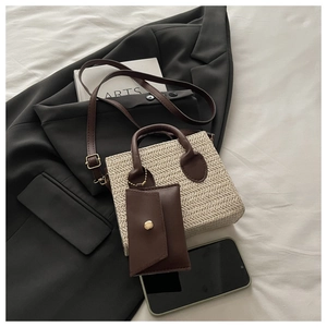Straw handbag with brown trim and mini pouch detail on white linen background