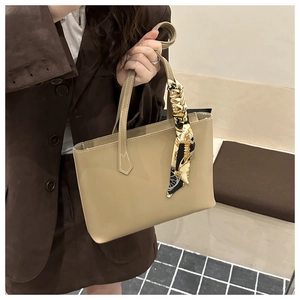 Detail of light khaki tote bag featuring white stitching and silk scarf on handle